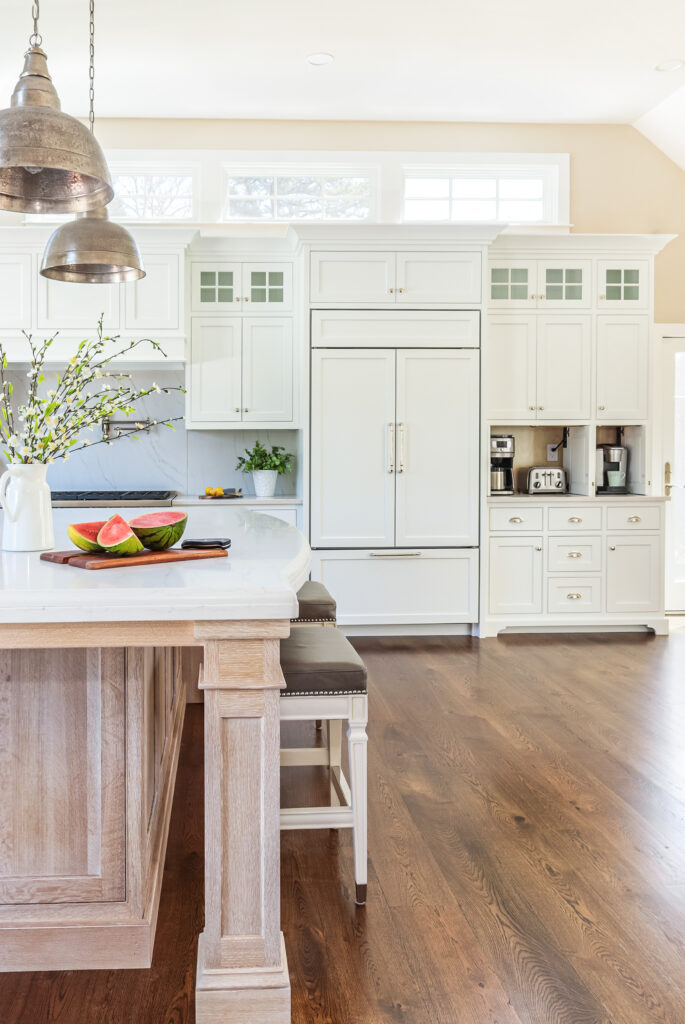 Wood Tones in Your Home | White kitchen with white-washed wood island and darker wood floors.